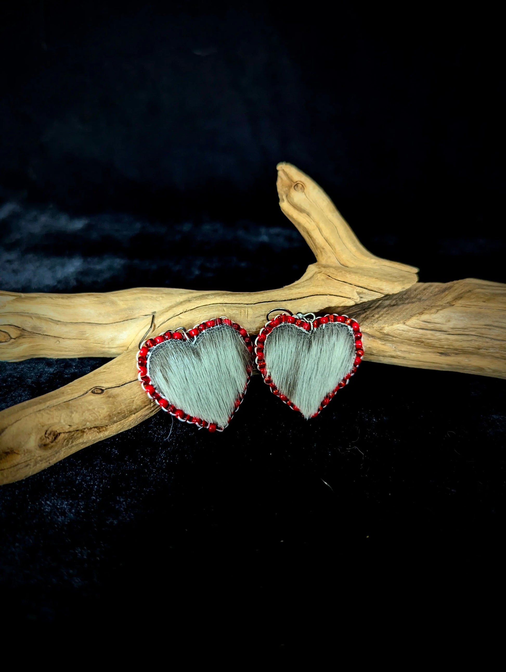 Heart-shaped earrings with red accents on a dark background