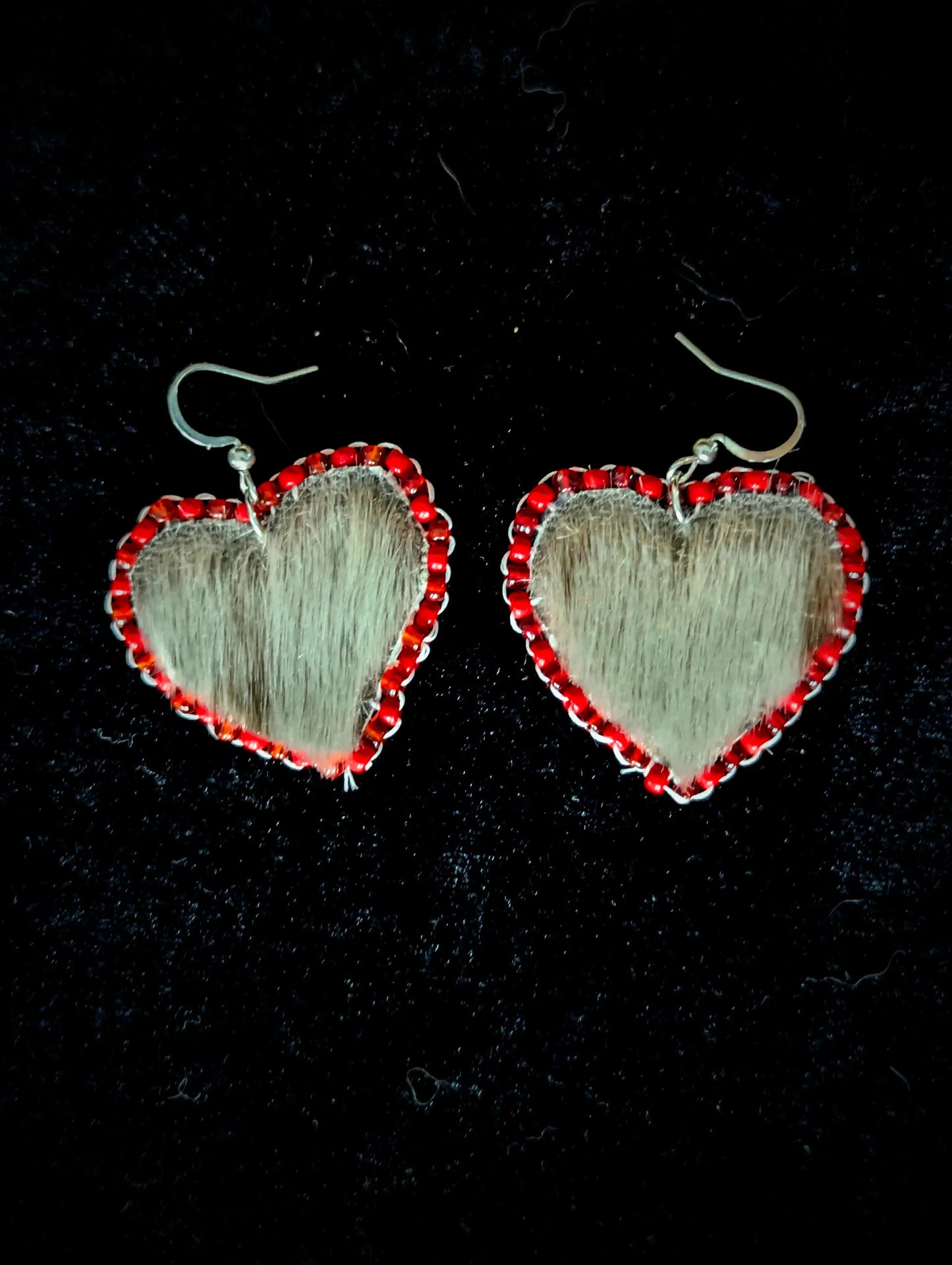 Heart-shaped earrings with red accents on a black background